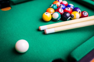 Bilardo sporu kavramı. Bilardo oynamak. Bilardo ıstakaları ve yeşil bilardo masasında çok renkli bilardo topu piramidi..