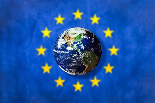 Flag of the European Union EU and a world globe in a middle.Blurred background.Elements of this image furnished by NASA.