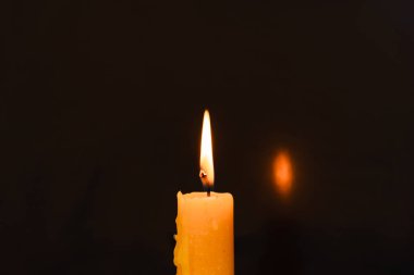 Karanlıkta mum yakmak. Tek bir mum ışığını kapat ve siyah arkaplanda alevi yak. Eritilmiş mum ışığı sınır tasarımı. Gece yanıyor, Karanlık. Mum ışığı. Uzayı kopyala..