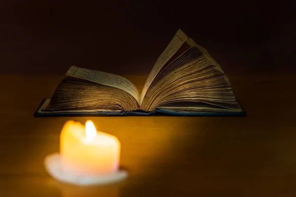 Religious concept.Holy Bible and candle on a old wooden table.Beautiful gold background.Beautiful,pleasant Religion concept.