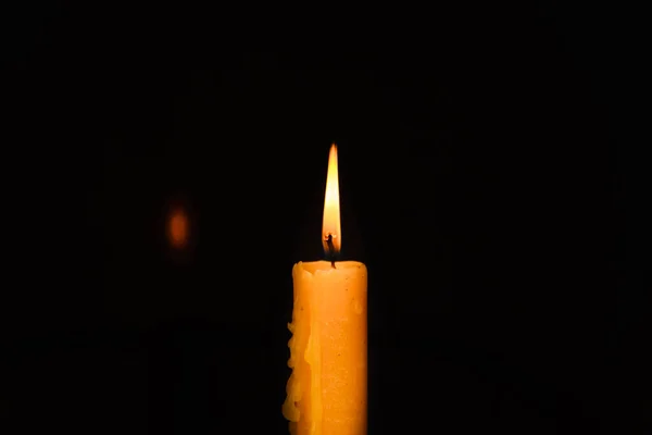 Old lighting a candle in the dark.Close up single candle light and flame on black background. Melted Wax Candle light border design. Burning at Night, Darkness.Candlelight.Copy space.