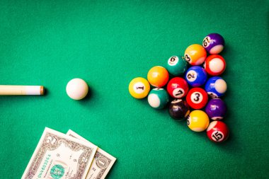 Kumar tutkusu. Para ve sayılı çok renkli bilardo topları. Oyun masasının üzerine dolar banknotları..