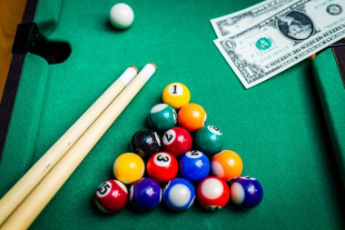 Kumar tutkusu. Para ve sayılı çok renkli bilardo topları. Oyun masasına dolar banknotları..