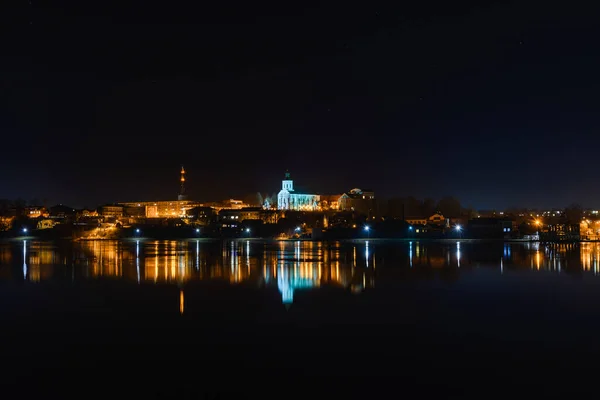 stock image Telsiai town,water night lake in Lithuania. Nice view winter of colorful houses on coast of frozen Lake.Nice winter night.Town colorful light reflections on water.Long exposure.