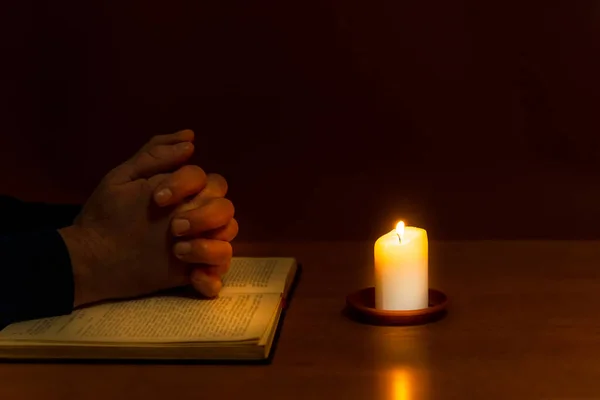 Religious concepts.The young payer prayed on the Bible in the room and lit the old candle to illuminate.Dark religion room.