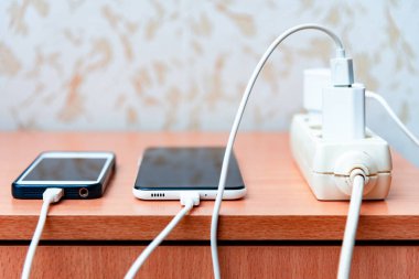 Elektrik prizi adaptör kablosu şarj edici ahşap masa üzerinde akıllı telefon. Şarj edildiğinde Mart cep telefonu.