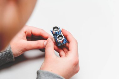 Öğrenci kız Arduino nano panosuna bakan Ultrasonik Uzaklık sensörlerini programlamayı öğreniyor. Kök projeler ve mini mühendislik projeleri bileşenleri oluşturuyor.