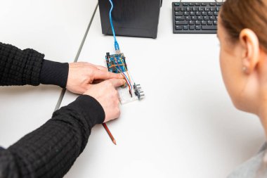 Öğretmen genç öğrencisine kök eğitim derslerinde yardımcı oluyor. Okul Sonrası Bilgisayar Kodlama Sınıfı Öğrencisi Robot Araç Programını Öğreniyor. Arduino Ultrasonik Kurulum.