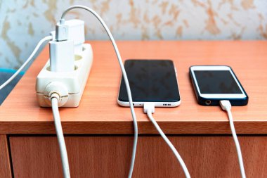 Elektrik prizi adaptör kablosu şarj edici ahşap masa üzerinde akıllı telefon. Şarj edildiğinde Mart cep telefonu.