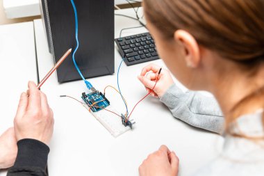 Öğretmen genç öğrencisine kök eğitim derslerinde yardımcı oluyor. Okul Sonrası Bilgisayar Kodlama Sınıfı Öğrencisi Robot Araç Programını Öğreniyor. Arduino Ultrasonik Kurulum.