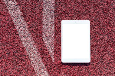 PC tablet düzlüğü arka planda spor kırmızı kauçuk üzerinde yatıyordu. Boş beyaz ekran, mockup.Üst görünüm. Mockup reklamı. İş kavramı. Boşluğu kopyala.