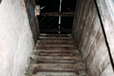 Garaja giden eski, hasarlı ahşap merdivenler. Tavan arasına giriş. Yukarı, tozlu karanlık merdivenler..