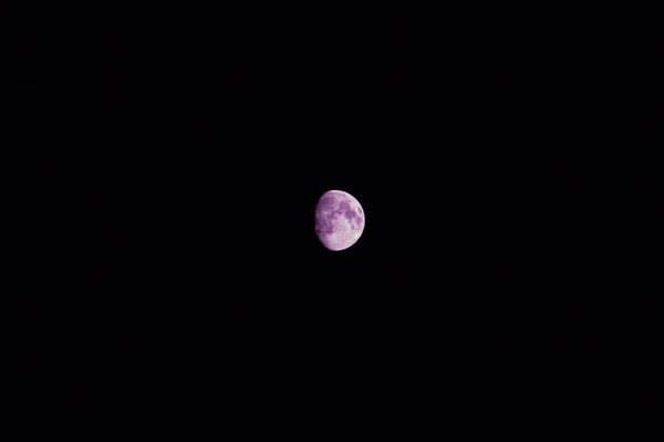 A purple,pink half moon in the night black dark sky.moon at night.Copy space.
