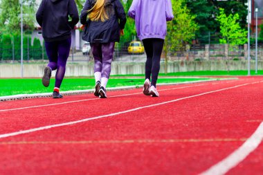 Stadyumda ya da arenada koşu bandında koşan bir grup genç. Spor giyimi eğitimi alan genç kızlar ve erkekler. Spor, spor, spor, başarı kavramı..