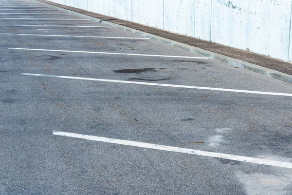 Gri arka planda boş park yeri. Asfaltlı park yerinde yol işaretleri var..