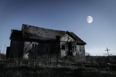 Spooky scene of haunted house and moon.Old mystic building at dead tree.Horror Halloween concept.Toned. clipart