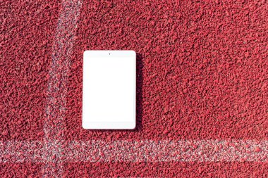 PC tablet düzlüğü arka planda spor kırmızı kauçuk üzerinde yatıyordu. Boş beyaz ekran, mockup.Üst görünüm. Mockup reklamı. İş kavramı. Boşluğu kopyala.