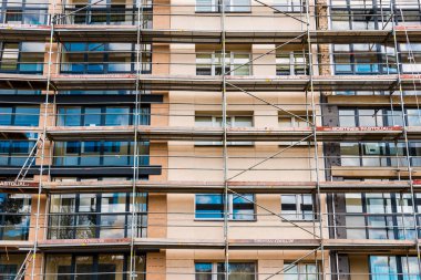 İnşaat iskelesi yenileme alanı. İnşaat alanının önündeki binanın dış görünüşü. Telsiai, Litvanya. 04-30-2023..