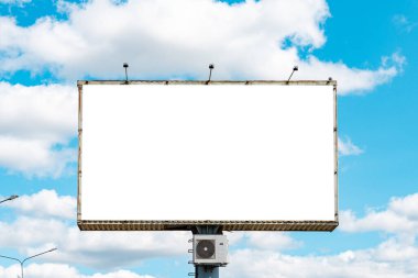 Reklamınız için mavi gökyüzünde boş bir ilan panosu. Boş bir ilan panosu, mavi bulutlu bir gökyüzüne karşı bir maket, mockup.Sıcak bir gün..
