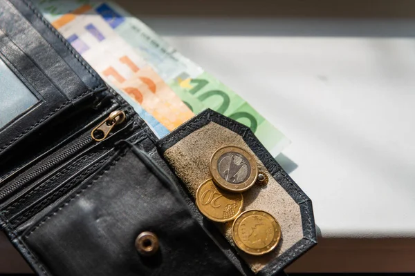 Black leather wallet with money euro inside it.Black wallet with euro money lying on the windowsill.Selective focus.