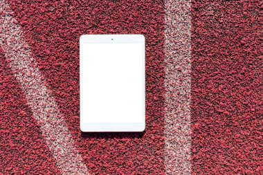 Boş beyaz ekran, mockup.PC tablet spor kırmızı kauçuk arka plan üzerine yatıyor.Üst görünüm. Mockup reklamı. İş kavramı. Boşluğu kopyala.