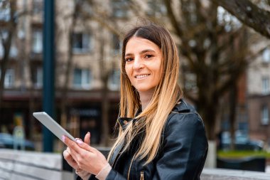 Genç hippi kız şehirde PC tableti tutuyor. Gezgin kadın tablet tablet üzerinde rehber kitap haritası kullanıyor, mobil internet kullanıyor. Kadın kısa mesaj ya da içerik mesajı yazıyor.