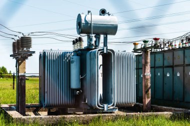 Mavi gökyüzüne karşı yüksek voltajlı trafo. Elektrik akımı yeniden dağıtımı. Kırsal gün.