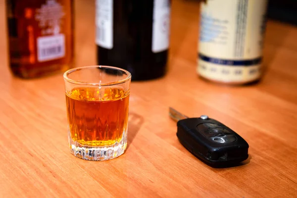 Drunk driving.Drink and auto keys.A glass of whiskey and car keys on the table.To drive or not to drive, alcohol addiction concept.