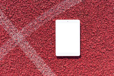 Boş beyaz ekran, mockup.PC tablet spor kırmızı kauçuk arka plan üzerine yatıyor.Üst görünüm. Mockup reklamı. İş kavramı. Boşluğu kopyala.