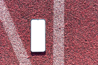 Akıllı telefon düzlüğü arka planda kırmızı spor lastiğinin üzerine yatıyordu. Boş beyaz ekran, mockup.Üst görünüm. Mockup reklamı..