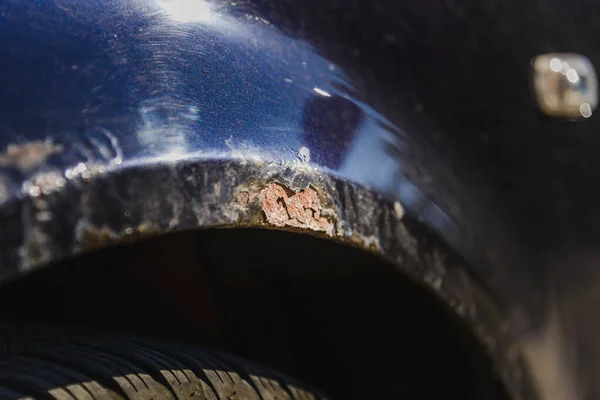 stock image Rust on the side of blue old car. Rust hole on old worn painted metal surface.Closeup.