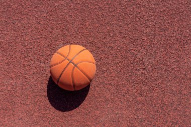 Basketbol topu kauçuk spor sahasında yatıyor. dışarıdaki kırmızı zemin. Üst manzara, fotokopi alanı. Basketbol pankartı..