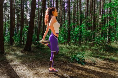 Genç bir kadın yaz günü dışarı çıkmadan önce esneme hareketleri yapıyor. Egzersiz ve Yaşam Tarzı konsepti. Mutlu bir hayat ve sağlık hizmeti teması. Doğa ve Açık hava teması.