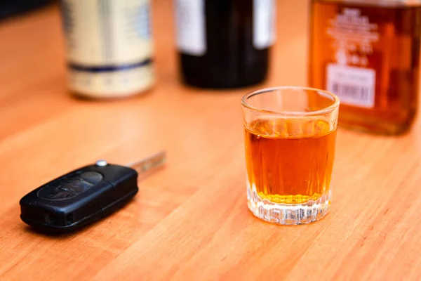 Drunk driving.Drink and auto keys.A glass of whiskey and car keys on the table.To drive or not to drive, alcohol addiction concept.