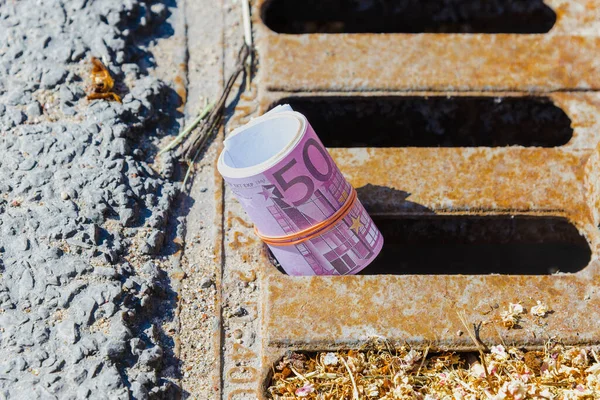 Eu 500 euro banknote down the street storm drain.Concept of senseless waste of money,loss,useless waste.