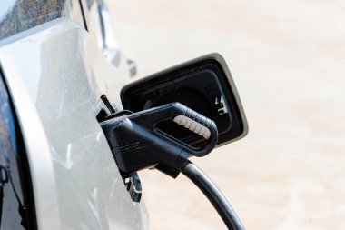 Elektrikli araba şarj ediliyor, Ulaşım Geleceği. Otoparkta elektrik değişiyor. İstasyonda elektrikli araba şarj ediliyor..