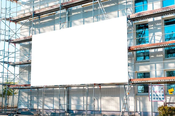 正在建设的现代建筑脚手架上挂着空白的白色广告 用白色广告牌重建一座建筑 — 图库照片