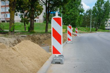 Yol tabelası ve kırmızı beyaz trafik konileri. Yeni asfalt kaldırım döşeme hazırlığı. Yol onarımı ve rodework konsepti. Uyarı işareti olarak caddedeki trafik konileri.