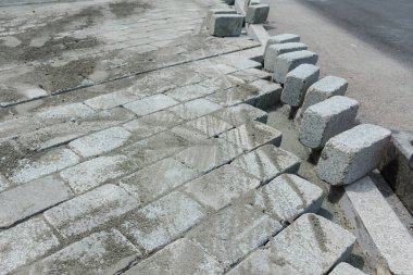 İnşaat alanında yol için önceden yapılmış beton kaldırım taşlarının kurulması ve düzenlenmesi.
