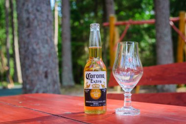 Bir şişe Corona Extra ve masada duran bira bardağı. Telsiai, Litvanya 06-25-2023..