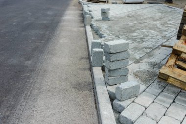 İnşaat alanında yol için önceden yapılmış beton kaldırım taşlarının kurulması ve düzenlenmesi.
