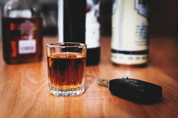 Drunk driving.Drink and auto keys.A glass of whiskey and car keys on the table.To drive or not to drive, alcohol addiction concept.