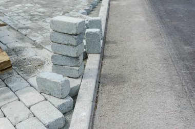 İnşaat alanında yol için önceden yapılmış beton kaldırım taşlarının kurulması ve düzenlenmesi.