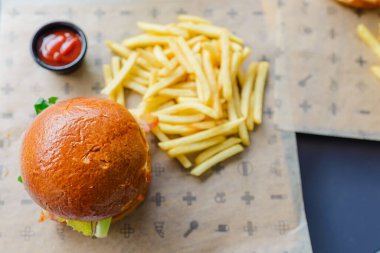 Açık hava restoranında servis edilen lezzetli bir hamburger. Izgara köftenin üstünde peynir, marul, domates ve soğan var. Taze bir bungda servis ediliyor. Seçmeli odak noktası, yakın çekim. Vilnius, Litvanya, 07-21-2023.