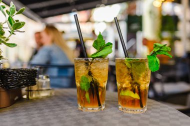 Alkol içeceği. Dışarıdaki Masa Kafe 'de. Alkollü bardaklar ve yarım limonlu, nane yapraklı. Limonlu kokteyl mojito ve nane yaprağı. Şehir hayatı. Kafenin arka planı bulanık. İyi akşamlar..