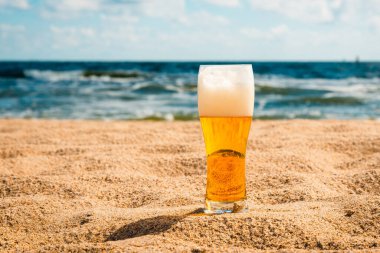 Hafif biralı bardak ya da sahilde rahatlamak için su damlacıklı bira. Kumda soğuk bira ve plaj arka planı. Boşluğu kopyala..
