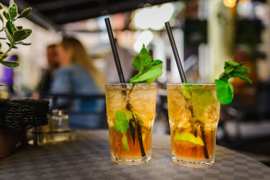Alkol içeceği. Dışarıdaki Masa Kafe 'de. Alkollü bardaklar ve yarım limonlu, nane yapraklı. Limonlu kokteyl mojito ve nane yaprağı. Şehir hayatı. Kafenin arka planı bulanık. İyi akşamlar..