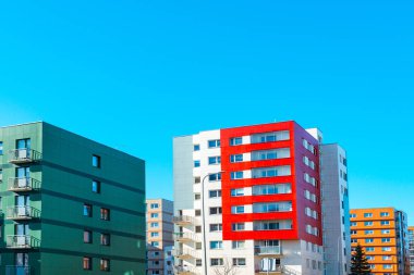 Satılık daireleri olan yeni yapılmış parlak renkli bir bina. Kırmızı turuncu ve yeşil apartman blokları. Yeni yenilenmiş konut alanında yeni bitirilmiş modern tarz apartman..