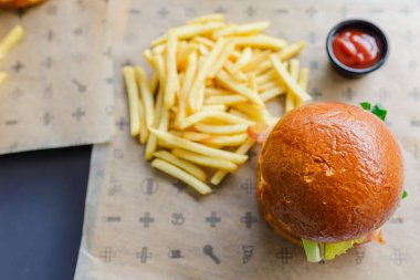 Açık hava restoranında servis edilen lezzetli bir hamburger. Izgara köftenin üstünde peynir, marul, domates ve soğan var. Taze bir bungda servis ediliyor. Seçmeli odak noktası, yakın çekim. Vilnius, Litvanya, 07-21-2023.