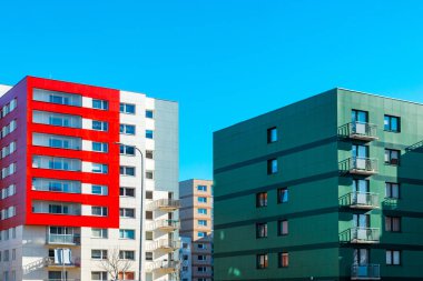 Kırmızı turuncu ve yeşil bloklar. Yeni yenilenmiş konut bölgesinde yeni bitirilmiş modern tarz bir apartman. Yeni yapılmış, parlak renklerde, satılık daireleri olan bir bina..